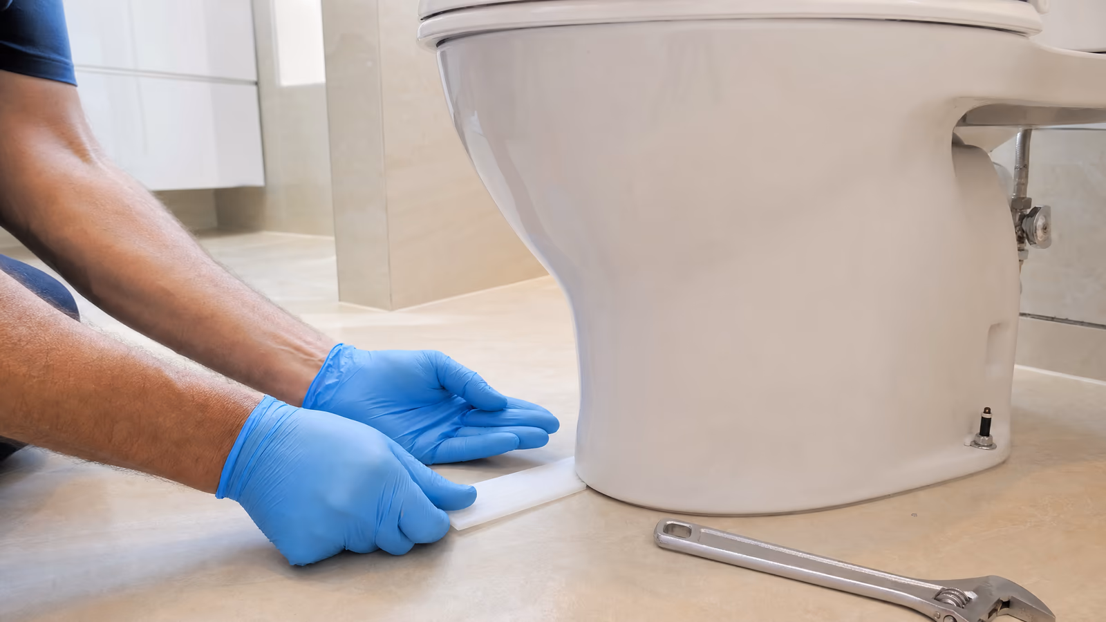 Technician leveling a loose, rocking toilet with shims